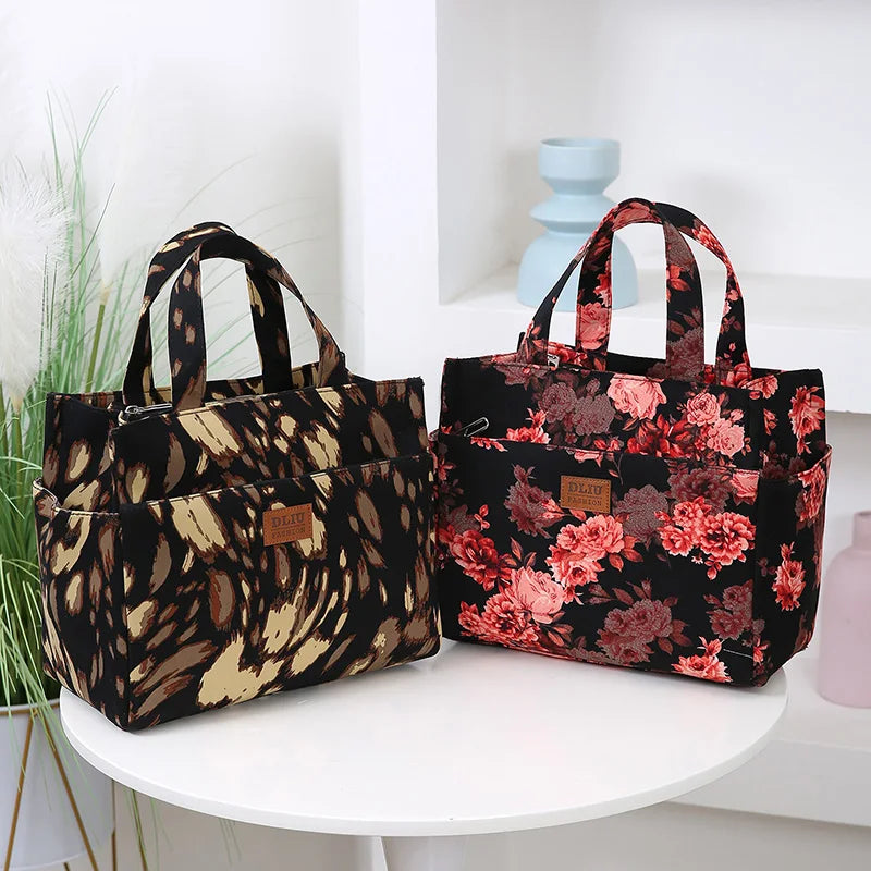 A pair of black cloth tote bags with floral patterns displayed on a white surface.