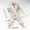 A beige floral patterned nylon shoulder strap with a silver buckle displayed on a white box.