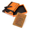 Une boîte orange avec un ruban noir et un portefeuille en cuir à l'intérieur, avec un message sentimental.