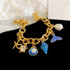 Gold charm bracelet featuring an ocean pearl, starfish, and shell accents.