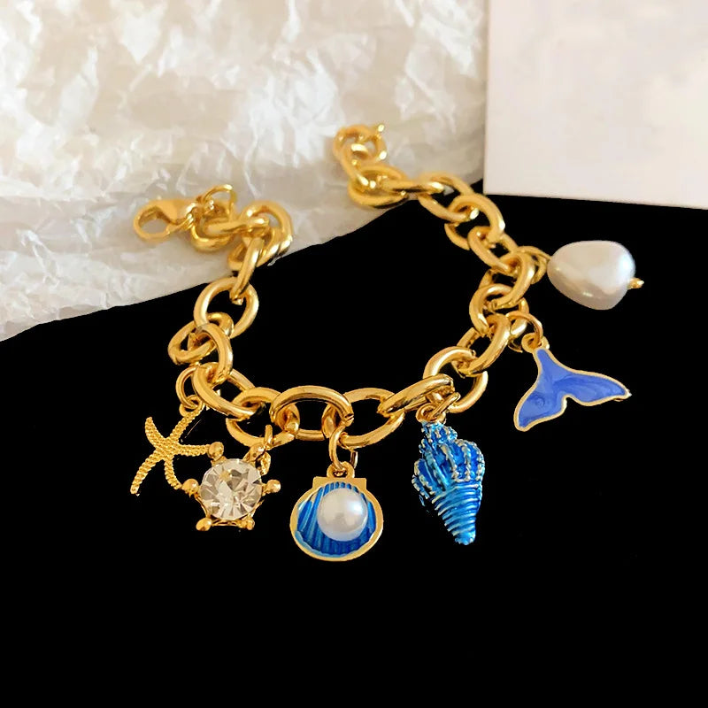 Gold charm bracelet featuring an ocean pearl, starfish, and shell accents.