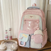 A pink Kawaii Harajuku backpack with a laptop compartment and various fabric accessories is displayed on a wooden surface.
