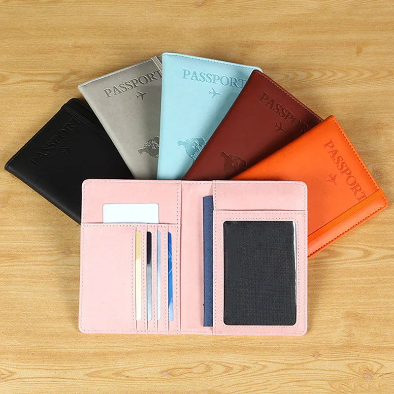 A collection of slim passport holders in various colors including black, gray, light blue, and orange resting on a wooden sur