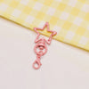 A pink star-shaped metal keychain clasp set resting on a yellow checkered cloth.