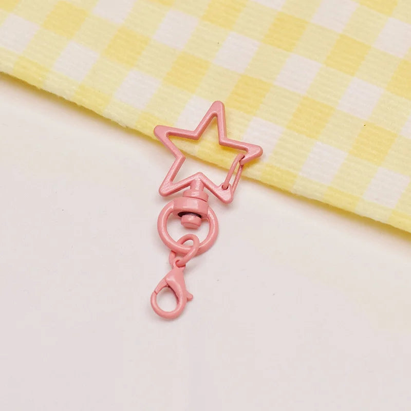 A pink star-shaped metal keychain clasp set resting on a yellow checkered cloth.