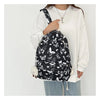A woman is wearing a black backpack with a white butterfly pattern and a white long-sleeved shirt.