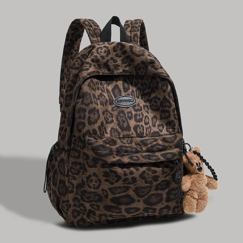 A brown leopard print backpack with a flap and pocket is shown against a gray background.