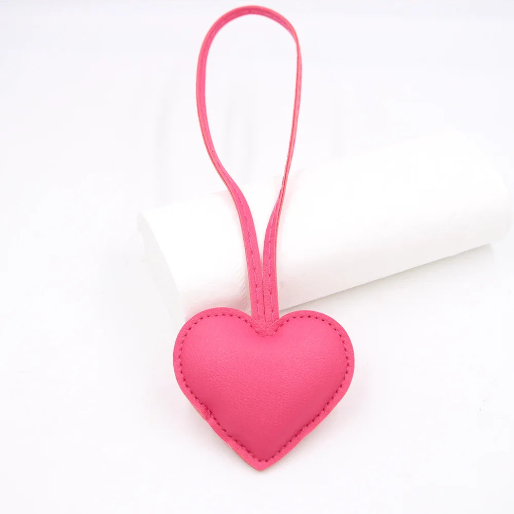 A pink PU leather heart-shaped keychain attached to a white cylindrical object.