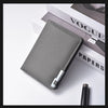 A gray slim vertical men's card wallet resting on a white surface next to a Vogue Papers magazine.
