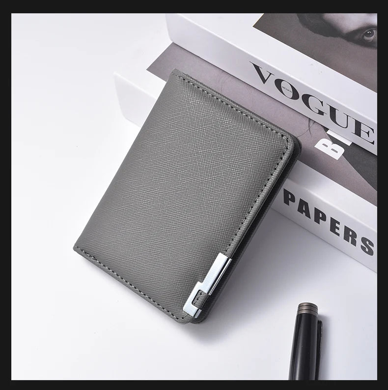 A gray slim vertical men's card wallet resting on a white surface next to a Vogue Papers magazine.
