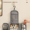 A gray waterproof hanging toiletry bag with compartments for brushes and toiletries is displayed on a white surface.