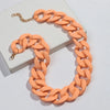 A necklace featuring a chain of matte orange acrylic links displayed on a white box.