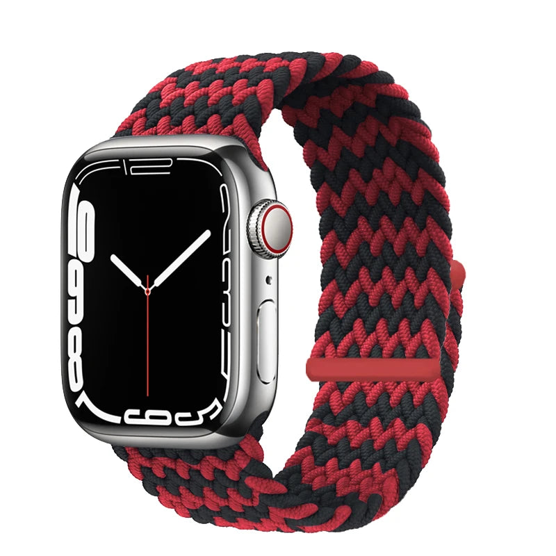 A silver Apple Watch is shown with a red and black braided stretch band on its wrist.