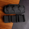 Black multi-slot travel watch organizer case with soft lining placed on a dark gray surface.