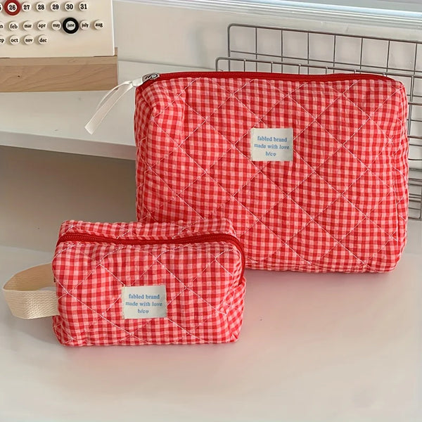 Sac de rangement cosmétique à carreaux rouge et blanc posé sur une surface blanche.