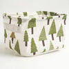 A natural linen storage basket with a white background and green pine tree pattern.