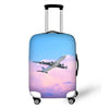 A light blue suitcase with a graphic of an airplane flying through pink and purple clouds.