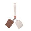 A light pink nylon zip wristlet coin purse with a matching strap and leather accent.
