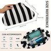 Pochette tissée rayée noir et blanc, tenue avec des petits objets comme un téléphone, un portefeuille, des lunettes de soleil