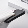 A hand holds a black ultra-thin PU leather credit card wallet with a gold coin inside on a white surface.