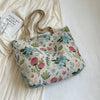 A beige bohemian corduroy tote bag with a floral pattern rests on a white fabric background.