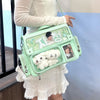 A light mint green Y2K transparent PU crossbody bag with a floral pattern and a white fluffy charm is being held by a person.