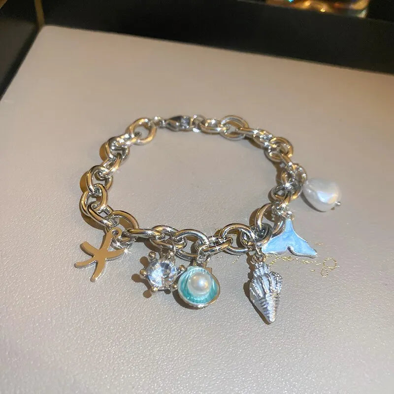 A silver charm bracelet featuring an ocean pearl, starfish, and shell accents.
