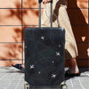 A black airplane pattern luggage protector cover is shown on a rolling suitcase next to a person's leg.