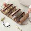 A beige portable detachable makeup bag with a clear window is shown next to cosmetic items on a white knitted surface.