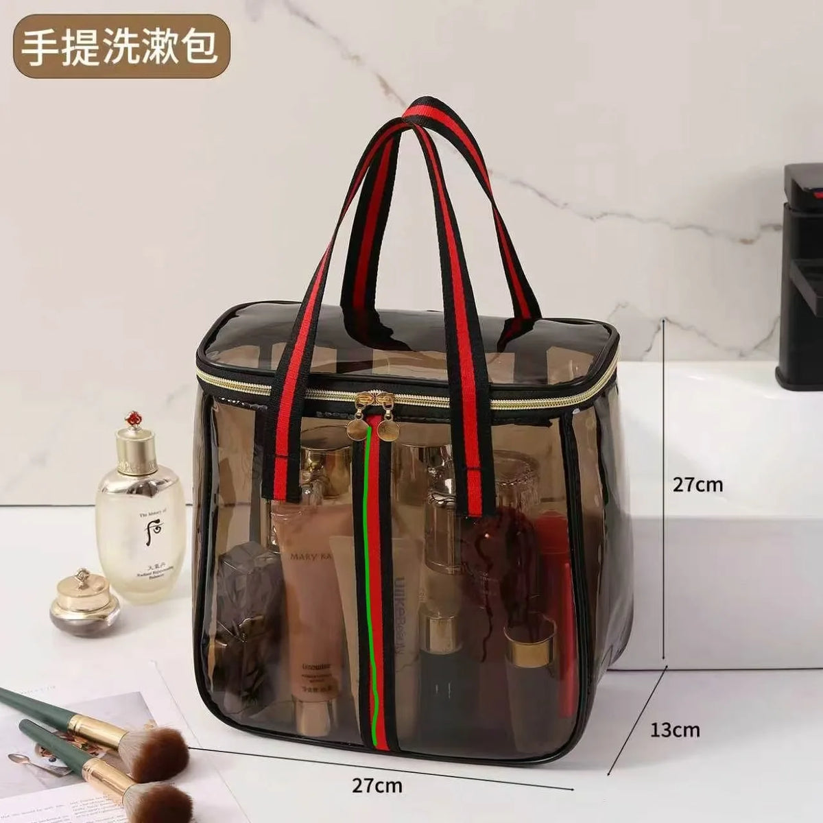 A clear waterproof travel toiletry bag with black and red striped handles and various grooming products displayed on a white 