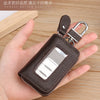 A brown leather car key case with a transparent window and silver clasp is held in a person's hand.