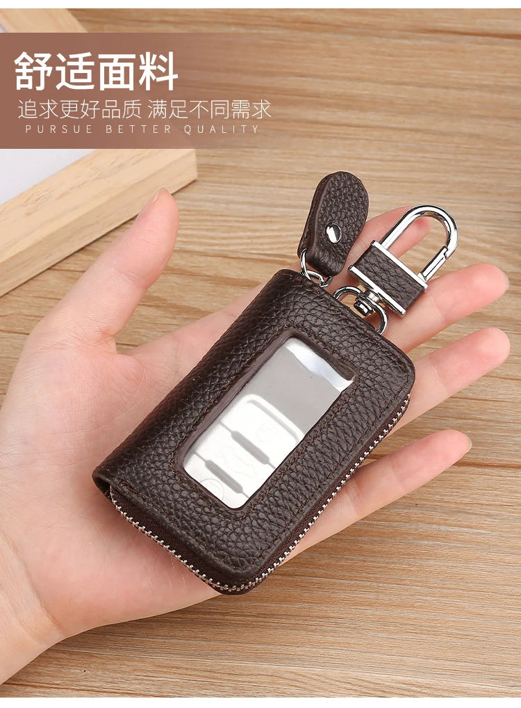 A brown leather car key case with a transparent window and silver clasp is held in a person's hand.