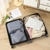 A black travel case holds a set of four gray and beige compression packing cubes and a white laptop.