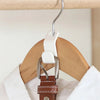 A multi-hook wardrobe organizer with white plastic hooks and a brown leather strap hanging from a wooden hanger.