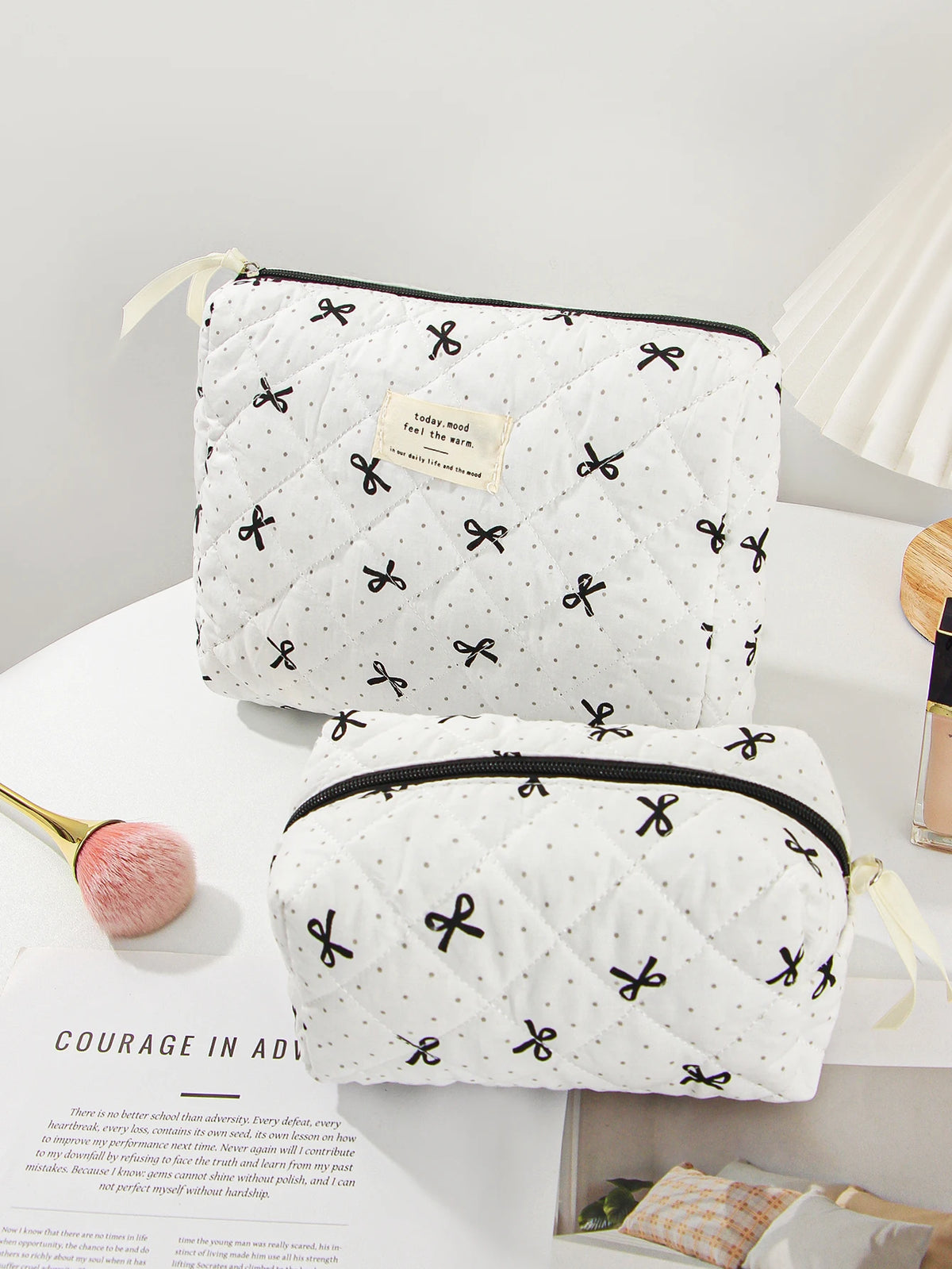 A quilted white makeup bag with black trim and a gold accent is shown on a white surface.