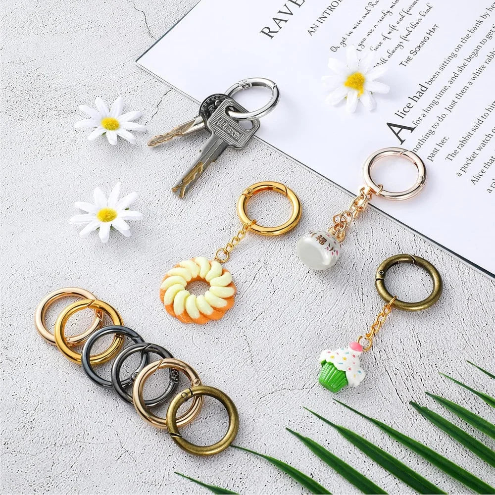A collection of stainless steel spring clasp keychain rings and carabiner clips with various decorative charms