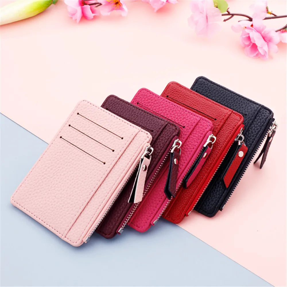 A collection of pink, magenta, and black PU leather card holder wallets with silver keychains displayed on a light background