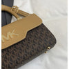 A tan Michael Kors letter square crossbody bag with a brown and black monogram pattern resting on a white surface.