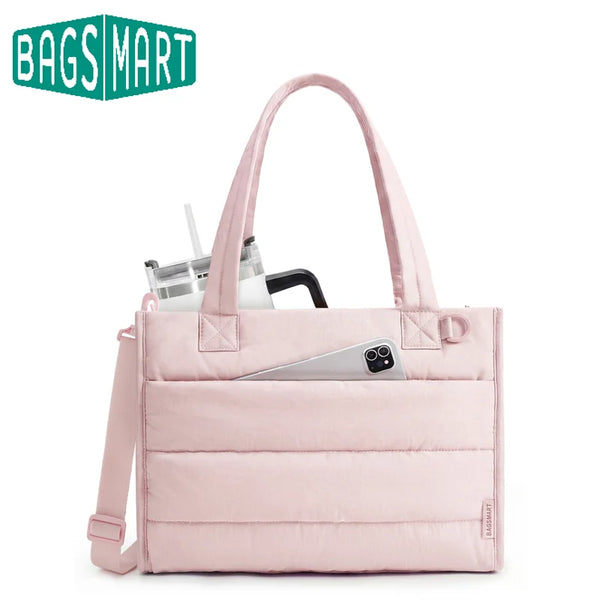 A pink quilted tote bag with a handle and pocket is shown next to a glass and a smartphone.