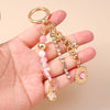 Gold and pink seashell starfish keychain with pearl accents displayed in a hand.