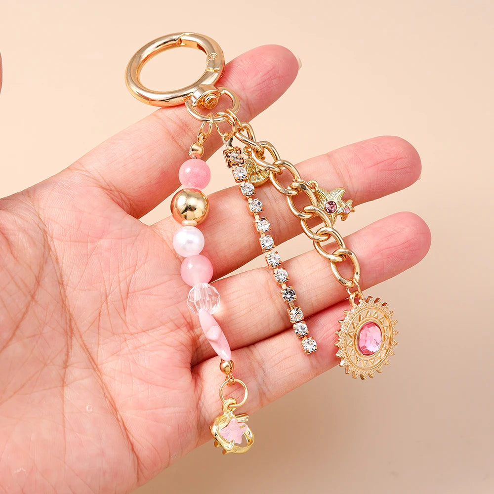 Gold and pink seashell starfish keychain with pearl accents displayed in a hand.
