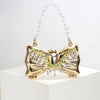 Gold acrylic bow clasp mini handbag with a clear crystal chain strap displayed on a white surface