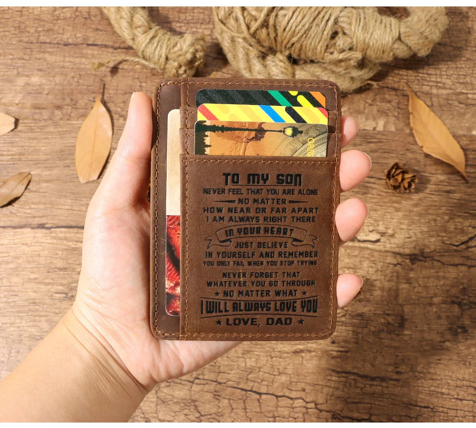 Portefeuille en cuir marron avec message personnalisé et carte colorée à l'intérieur, tenu dans une main sur une surface en b