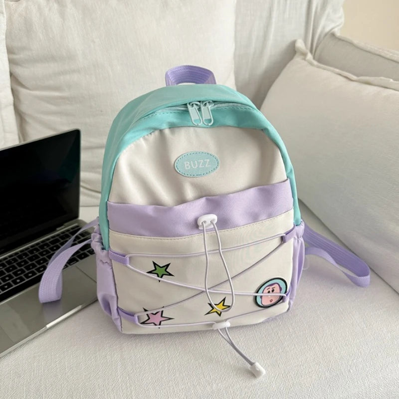 A light purple and mint green fashion backpack with a white cow print design resting on a white surface.