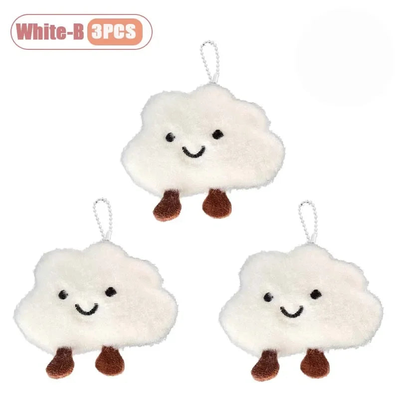 Three white cloud-shaped plush keychains or brooch pins