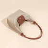A beige waterproof nylon crossbody bag with dual brown leather straps shown from the side.