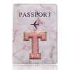 Portafolio de pasaporte de cuero marmolado rosa con inicial T dorada y símbolo de avión.