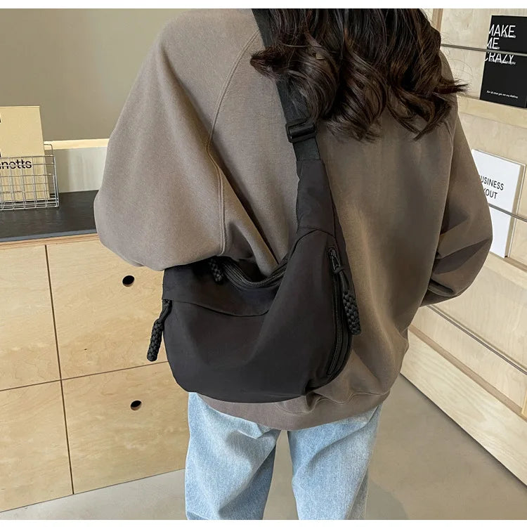 Eine Frau von hinten, die ein braunes, oversized Hemd und eine schwarze Nylon-Umhängetasche trägt.