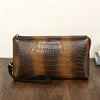 Clutch de estampado de cocodrilo marrón sobre una superficie de madera oscura.