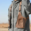 Nahaufnahme einer braunen taktischen Storage-Westtasche, befestigt an Reißverschluss und Riemen einer grauen Outdoor-Jacke.